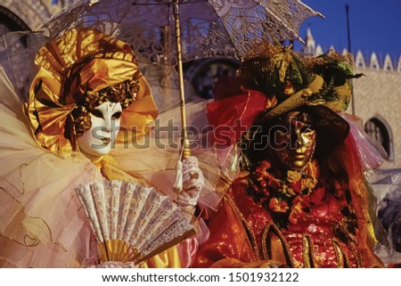 Carnival revelers wearing colorful and sophisticated costumes with masks in Piazza San Marco at the Carnival of Venice. The historic and amazing marine city full of canals and palaces in Italy.