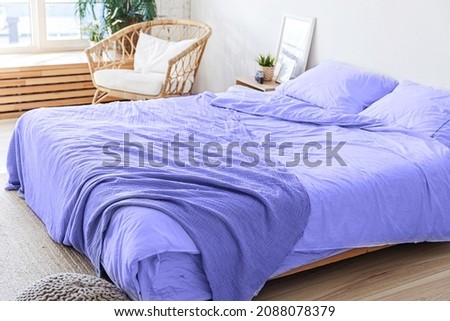 Loft bedroom interior, bed linen colored in trendy color of year 2022 Very Peri background. Inspired by using color 17-3938, Color of the year concept. Minimalist home design Scandinavian style