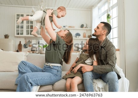 Similar – Image, Stock Photo Parents laughing and having fun with their baby son sitting at the home terrace, with beautiful sunset light.