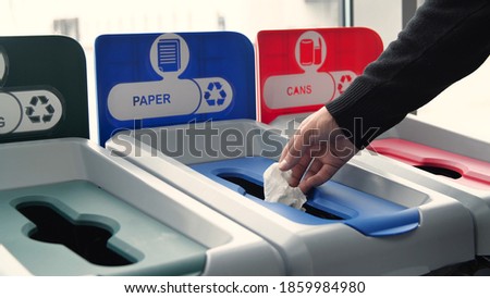 Close-up of man throwing garbage into sorting bins. Media. Man throws garbage into colored bins for sorting. Sorting garbage helps in recycling and supports ecology of nature