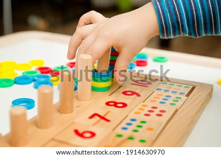 Child playing with different color wooden rings. Sequence, fine motor skills, therapy task for education and brain exercise. Counting math play game.  Montessori type implement. Wooden toys.