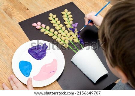 Boy painting with a gouache spring flower. Boy making color paper hyacinths for mommy. Children activities, easy ideas for kids at home. Art lessons at home. DIY tasks for children. Early pre - school