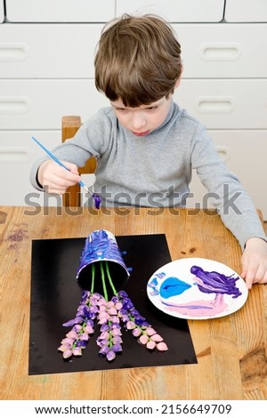 Boy painting with a gouache spring flower. Boy making color paper hyacinths for mommy. Children activities, easy ideas for kids at home. Art lessons at home. DIY tasks for children. Early pre - school