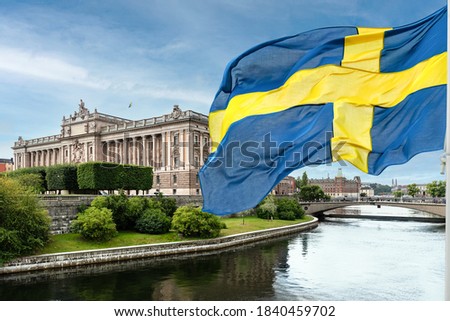 The building of the Swedish Parliament (Riksdag) and the Riksbank Bridge over the Lilla Vartan Strait with the national flag of Sweden in the foreground. Foto stock © 