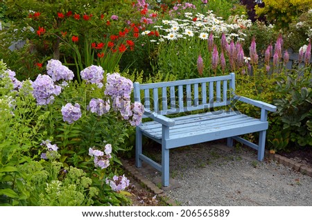Old blue wooden garden bench in colorful summer garden
