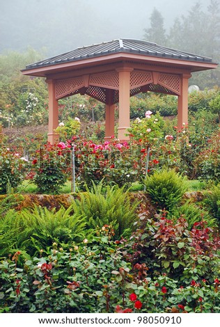 Ornamental wooden gazebo in rose garden with mist in background