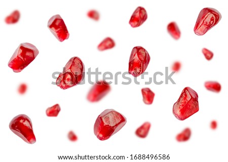 Falling pomegranate grains isolated on a white background, selective focus. Pomegranate seeds in the air on a white background. Set of pomegranate seeds in the air. Pomegranate seeds fall.