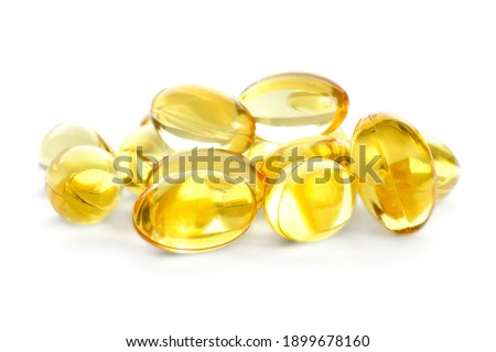 Fish oil gel capsules isolated on white background. Pile of yellow fish oil capsules isolated on white background. Omega-3 fish oil capsules. Close-up of yellow fish oil capsules.