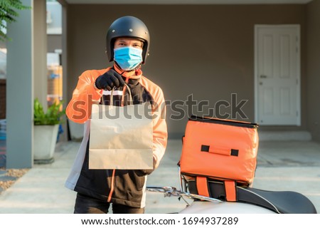 Delivery Asian man wear protective mask in orange uniform and ready to send delivering Food bag in front of customer houes with case box on scooter, express food delivery and shopping online concept.