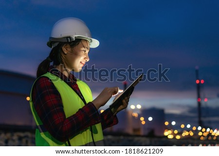 Asian woman petrochemical engineer working at night with digital tablet Inside oil and gas refinery plant industry factory at night for inspector safety quality control.