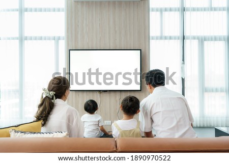 Asian happy family sitting and watching television in living room at home and spent quality time together for activity in vacation day, holiday, happiness or lifestyle concept.