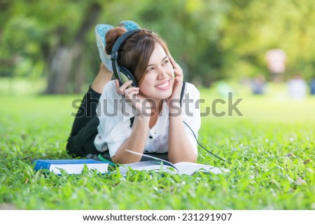 Asian student with Headphones Outdoors. Enjoying Music