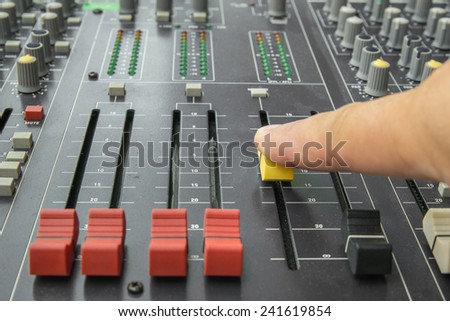 Finger pushing a mixing desk slide. Selective focus