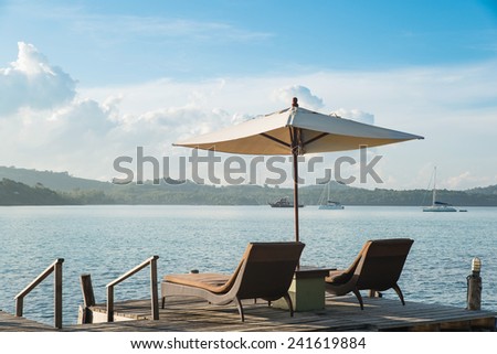 Two chairs beach and umbrella on wooden desk against blue sky. Summer travel in Phuket ,Thailand.