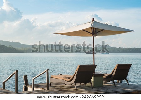 Two chairs and umbrella on wooden desk against blue sky.Summer Travel in Phuket ,Thailand.