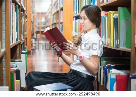 Asian student in uniform reading in the library at university