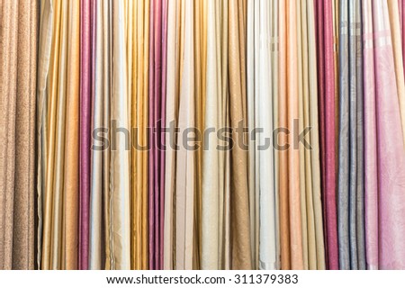 Colorful curtain samples hanging from hangers on a rail in a display in a retail store