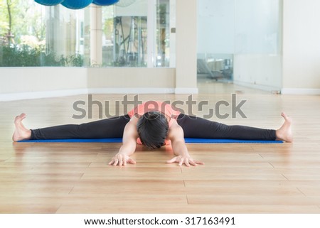 Asian woman make yoga Wide-angle seated forward bend pose in classroom