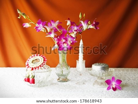 still life with glass bowl,vase,orchid,silver bowl,glass tray with pedestal,candle and jasmine garland.