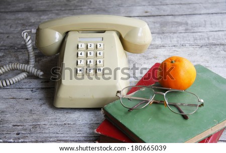 still life with old book,glasses,Push Button Telephone and orange on wooden table.