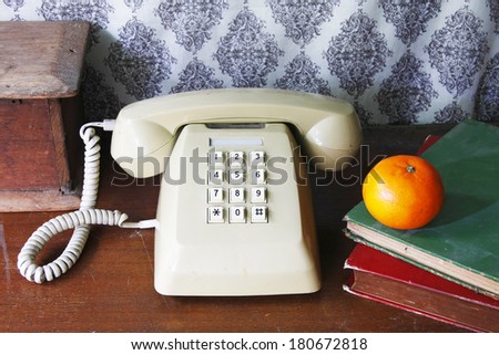still life with old book,Push Button Telephone and orange on wooden table.