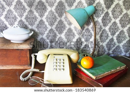 still life with old book,Push Button Telephone,glasses and tea cop,lamp and orange on wooden table.