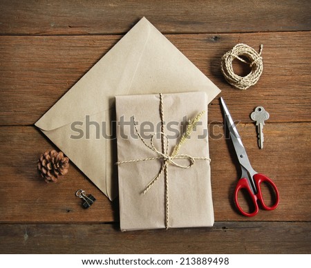 still life with postal parcel wrapped in brown paper and the contents of a workspace composed. Different objects on wooden table.