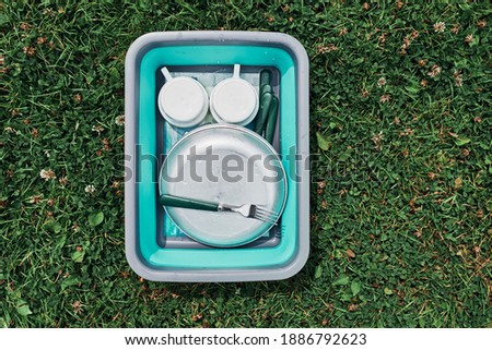 Similar – Image, Stock Photo Washing up bowl filled with the washed outdoor dishes, plates, cups and cutlery put on grass