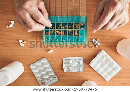 Similar – Image, Stock Photo Senior man organizing his medication into pill dispenser. Senior man taking pills from box