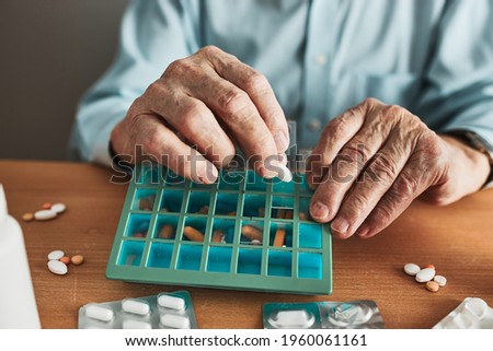 Similar – Image, Stock Photo Senior man organizing his medication into pill dispenser. Senior man taking pills from box