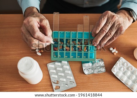 Similar – Image, Stock Photo Senior man organizing his medication into pill dispenser. Senior man taking pills from box