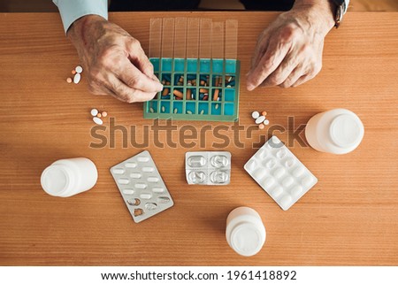 Similar – Image, Stock Photo Senior man organizing his medication into pill dispenser. Senior man taking pills from box