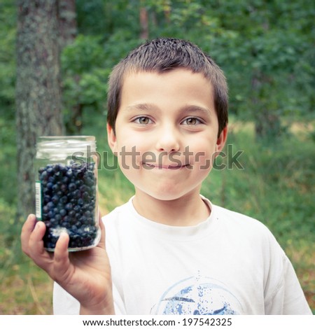 Little boy holding a jar of blueberries