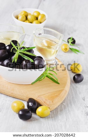 different marinated olives, rosemary and olive oil on a cutting board.selective focus. health and diet