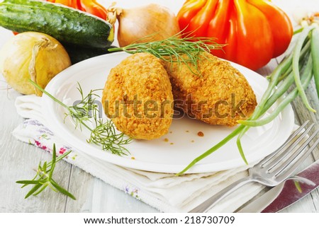 breaded cutlets on a plate and fresh vegetables on the table. cutlets kievski