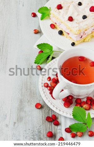 strawberry tea and a piece of cake with blueberries and strawberries on old wooden background.copy space background