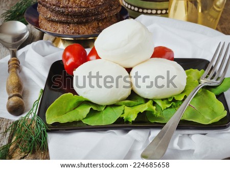 fresh mozzarella cheese on a plate, spinach and tomatoes on an old rustic table. health and diet food