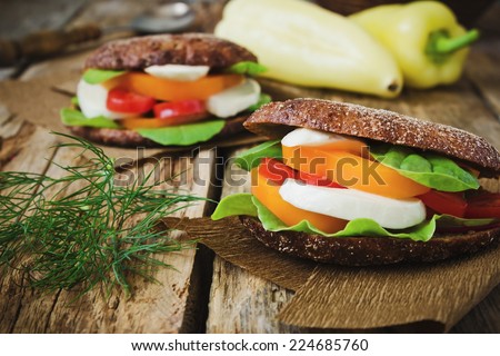 sandwiches with mozzarella, tomatoes, paprika and spinach on the old wooden background.health and diet food