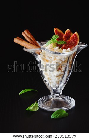 delicious curd dessert with sliced fruit, cinnamon and fresh mint leaves on a black background. health and diet food
