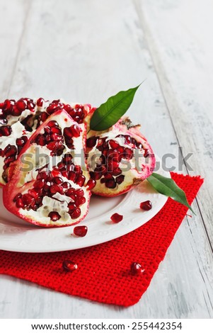 ripe pomegranate seeds on a plate on the painted wooden background. health and diet food