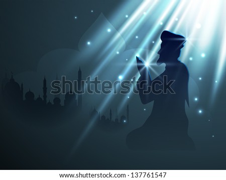 Silhouette of Muslim person in traditional dress reading Namaj (Islamic Prayer) on blue background with text Ramadan Kareem.