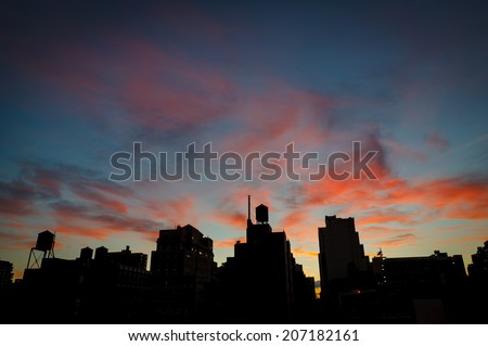 Blue hour over Chelsea rooftops and water towers, Manhattan, New York City. twilight draws the contours of Chelsea rooftops and water towers under a dark blue sky and red clouds. Cityscape, Manhattan.
