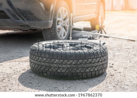 Replacing the wheel on the road by the driver. Replacement of tires on the car by a mechanic after balancing the wheels in close-up. The prepared wheel lies on the ground next to the car Stock fotó © 