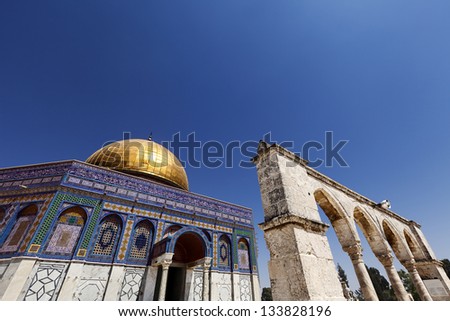 The Dome Of The Rock in the old city of Jerusalem, one of the holiest places to the Islam, from a low and wide angle view, with one of the arches leading to it.