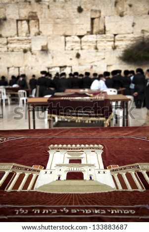 A velvet cloth embroidered with an image of the original Jewish Many orthodox religious Hassidic people are praying at the wailing wall, the only remains from the temple depicted on the cloth.