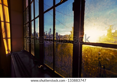 One World Trade Center (aka Freedom Tower) and Lower Manhattan skyline seen through soft focus angle of a window. Back lit by afternoon yellow sun on a rooftop West Village apartment.