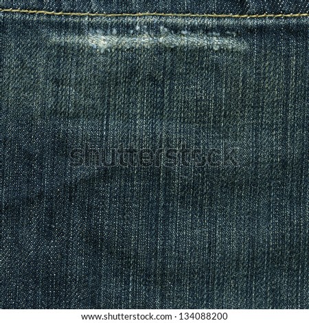 High resolution scan of blue denim fabric with a wear-out mark and stitch crossing.