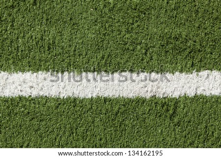Close up of artificial lawn with a white stripe painted on it. Part of a sports field.