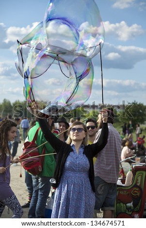 BERLIN - JUN 10: Young woman making giant soap bubbles on a summer day at Mauerpark. On June 10 2012 in Berlin, Germany.