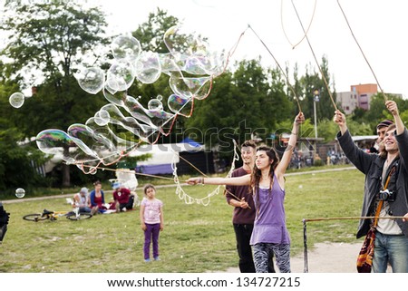 BERLIN - JUN 10: Young adults are making giant soap bubbles on an early summer day at Mauerpark, on June 10 2012 in Berlin, Germany.